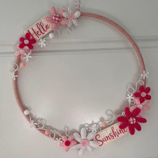 Pink yarn wreath with felt flowers and Hello Sunshine banners.