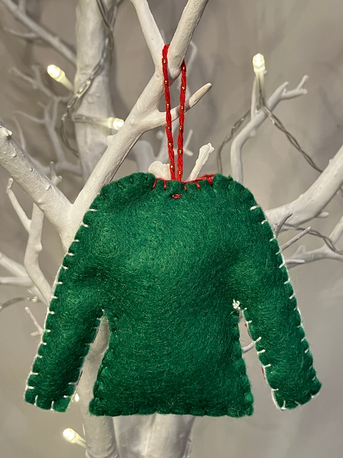 Green felt Christmas sweater ornament with red stitching and hanger.