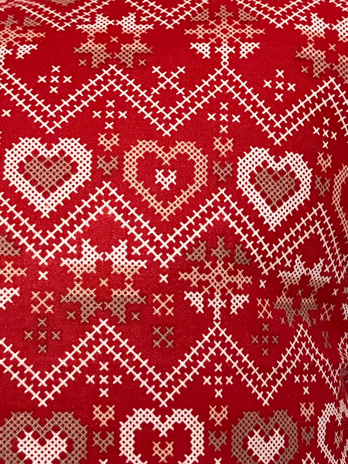 A close-up of the red pillow with a white and gold heart-patterned fabric.