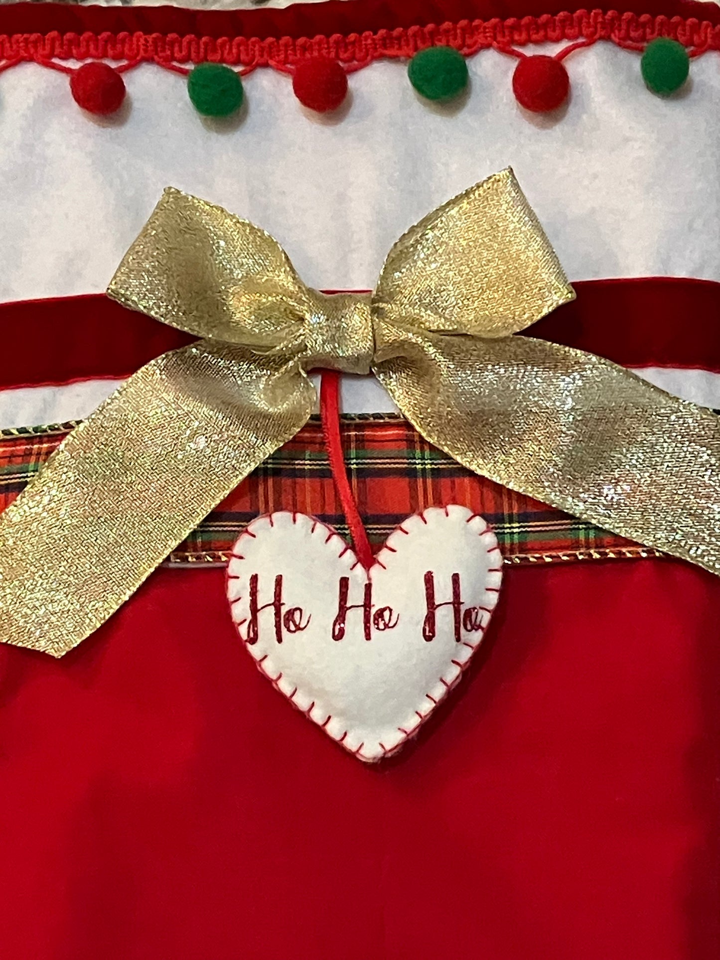 Close-up of the gold bow and "Ho Ho Ho" heart on the Christmas stocking.