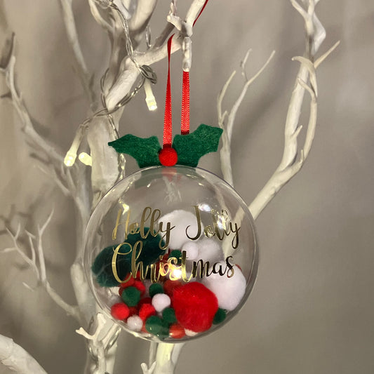 Clear Christmas bauble with red and green pom-poms, holly, and "Holly Jolly Christmas" text.