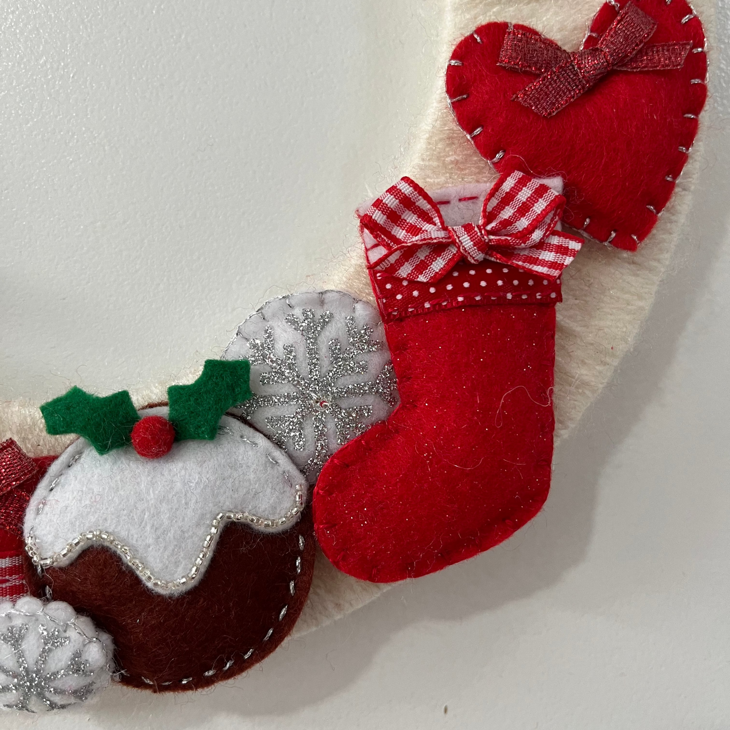 Close-up of a Christmas wreath with a red heart, stocking, and Christmas pudding.