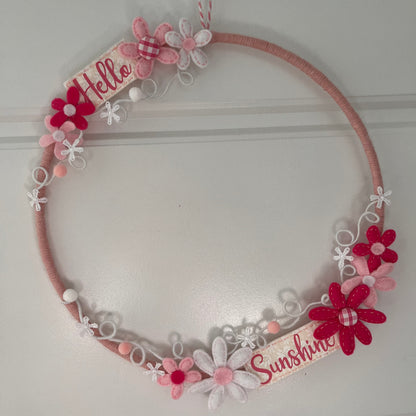 Pink yarn wreath with felt flowers and Hello Sunshine banners.