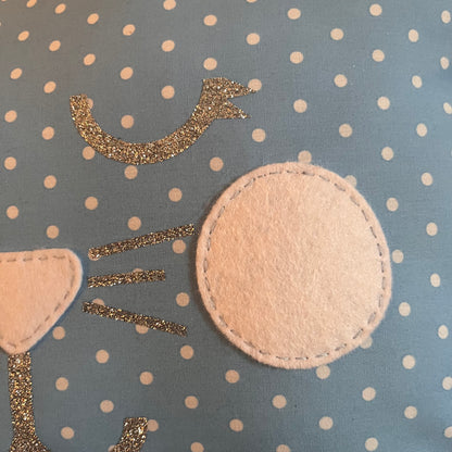 Close-up of a blue polka dot fabric with white felt and silver glitter embellishments.