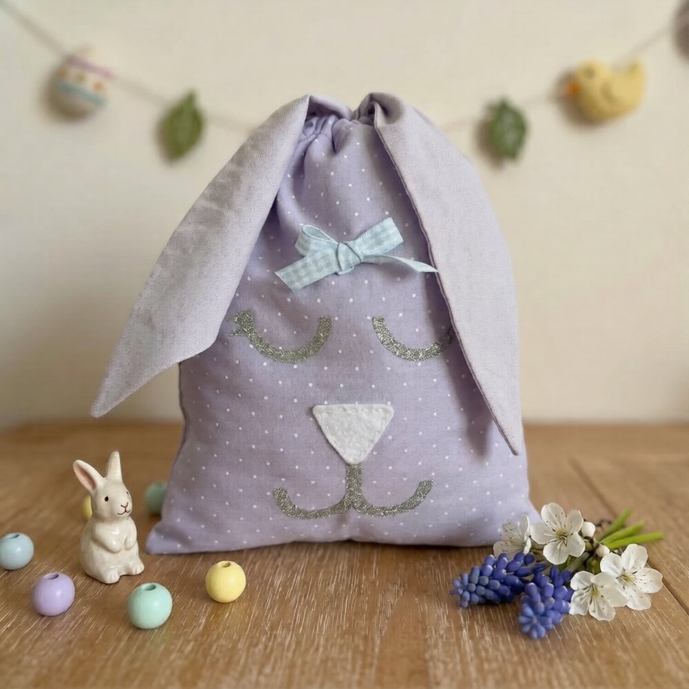 Purple polka dot bunny bag with long ears, a blue bow, and glitter details for eyes and mouth
