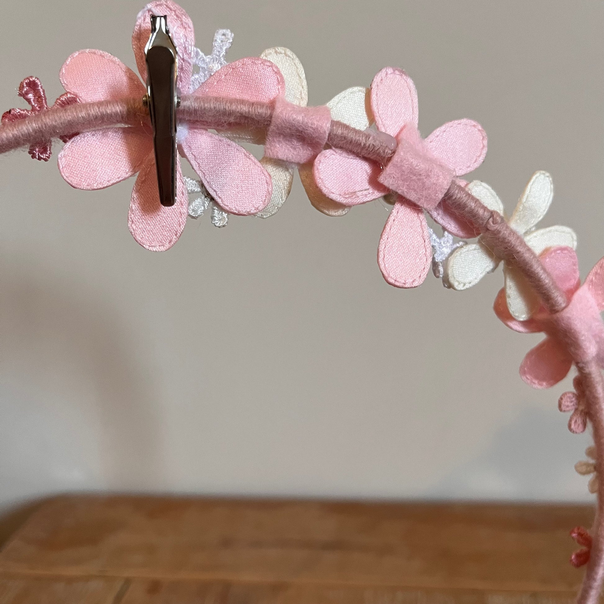 Pink and white fabric flowers on a headband, with a silver clip attached.