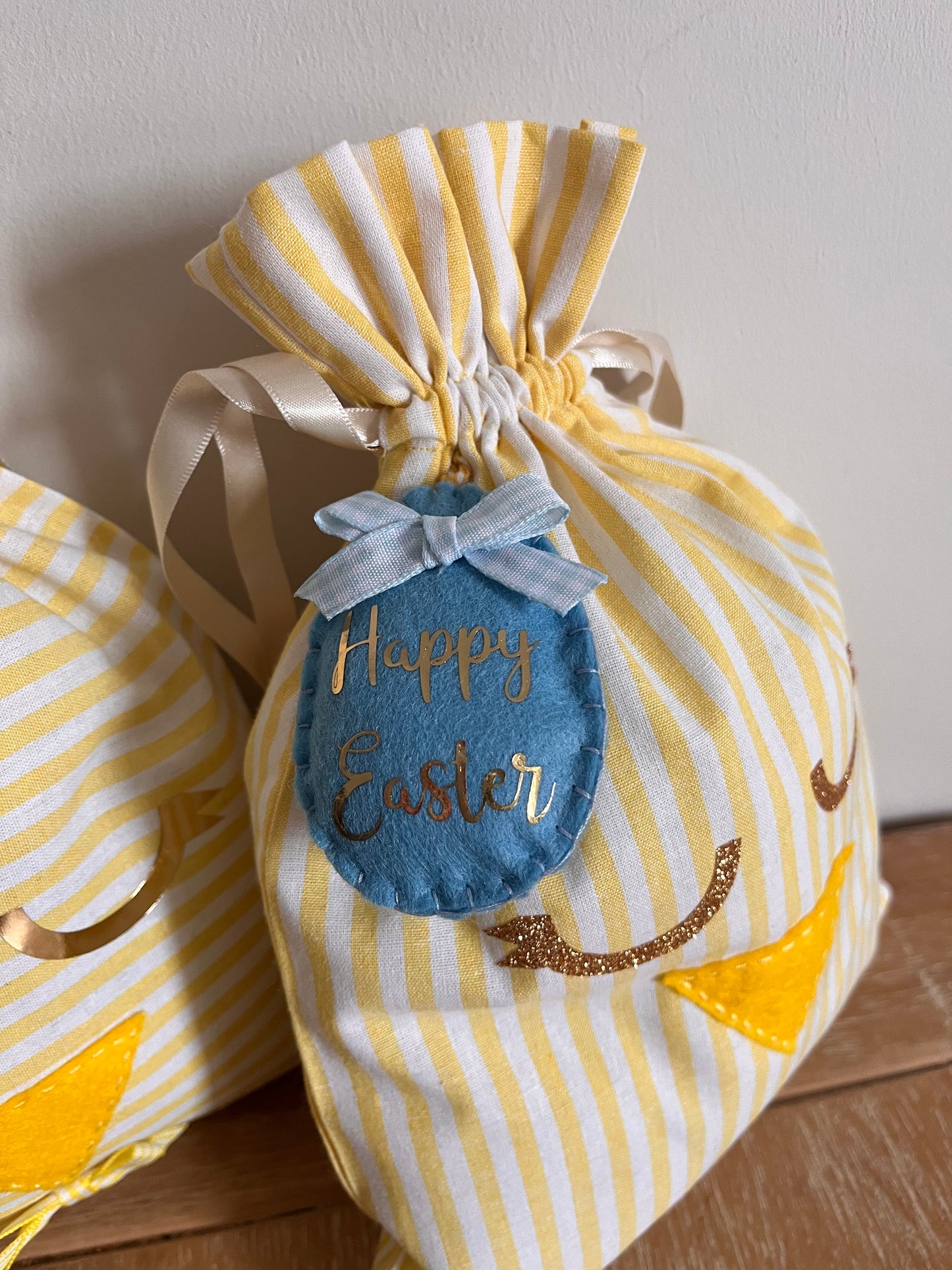 Yellow and white striped Easter gift bag with a blue felt egg tag that says Happy Easter.