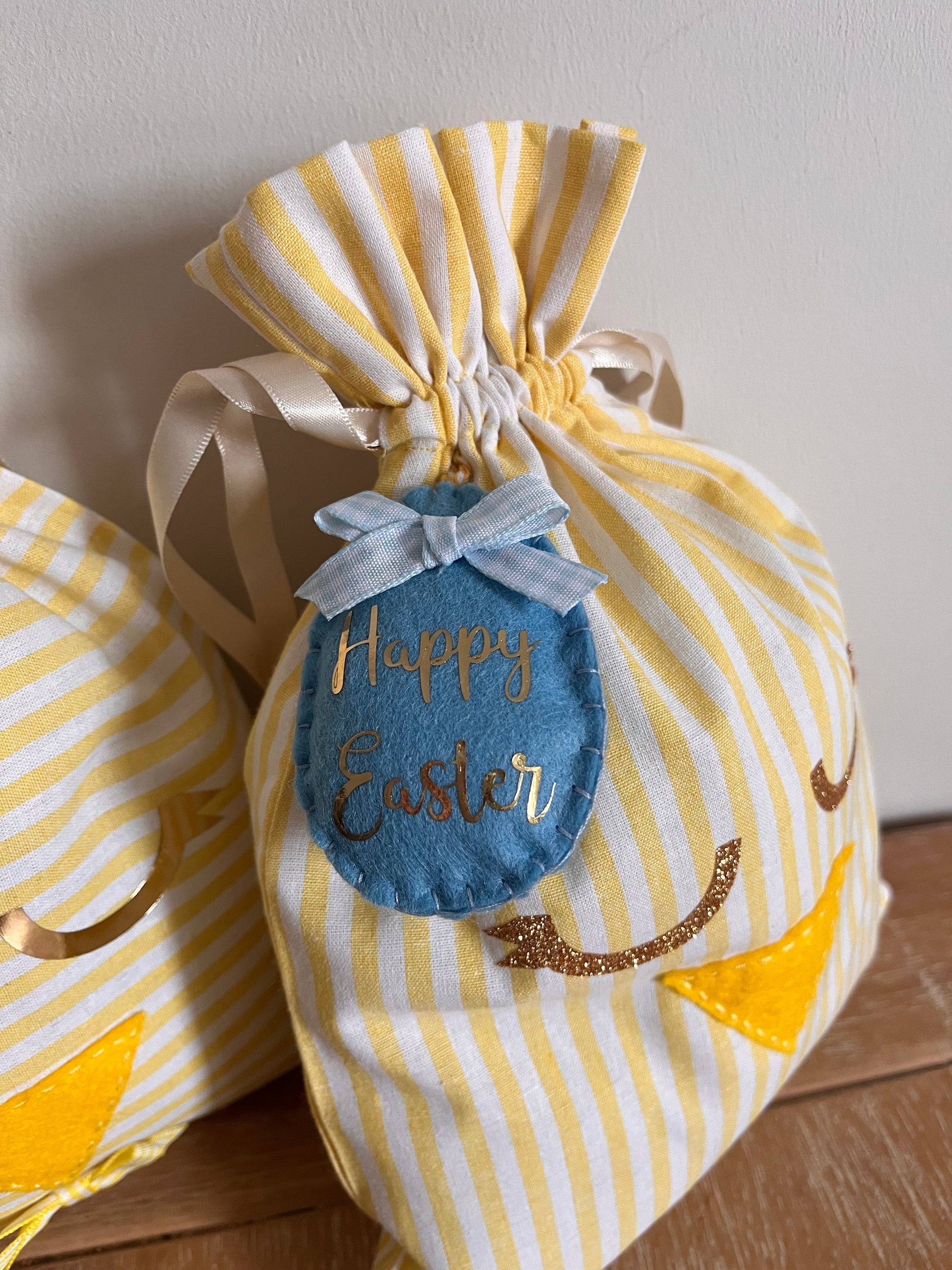 Yellow and white striped Easter gift bag with a blue felt egg tag that says Happy Easter.