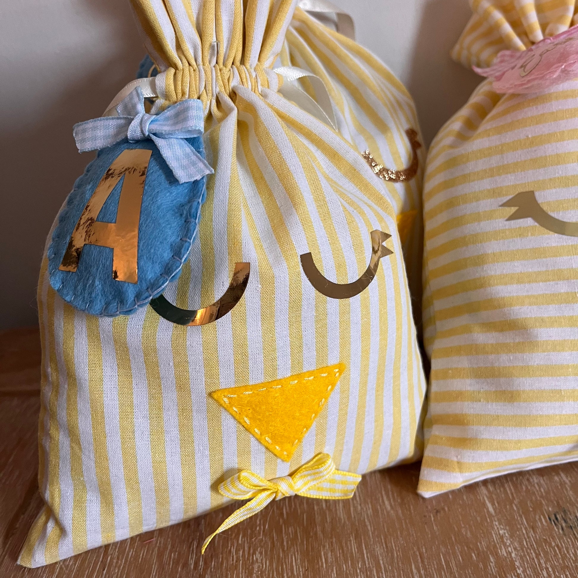 Yellow and white striped fabric bag with a chick face, a blue felt number 4, and a yellow bow.