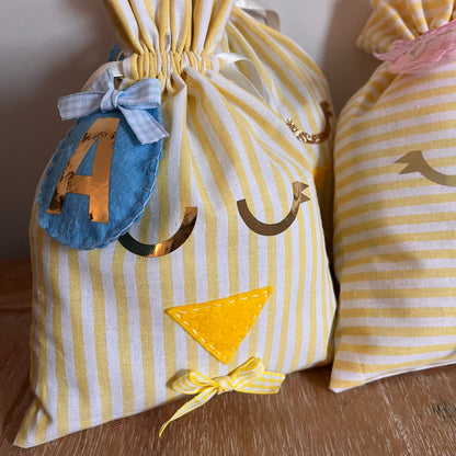 Yellow and white striped fabric bag with a chick face, a blue felt number 4, and a yellow bow.