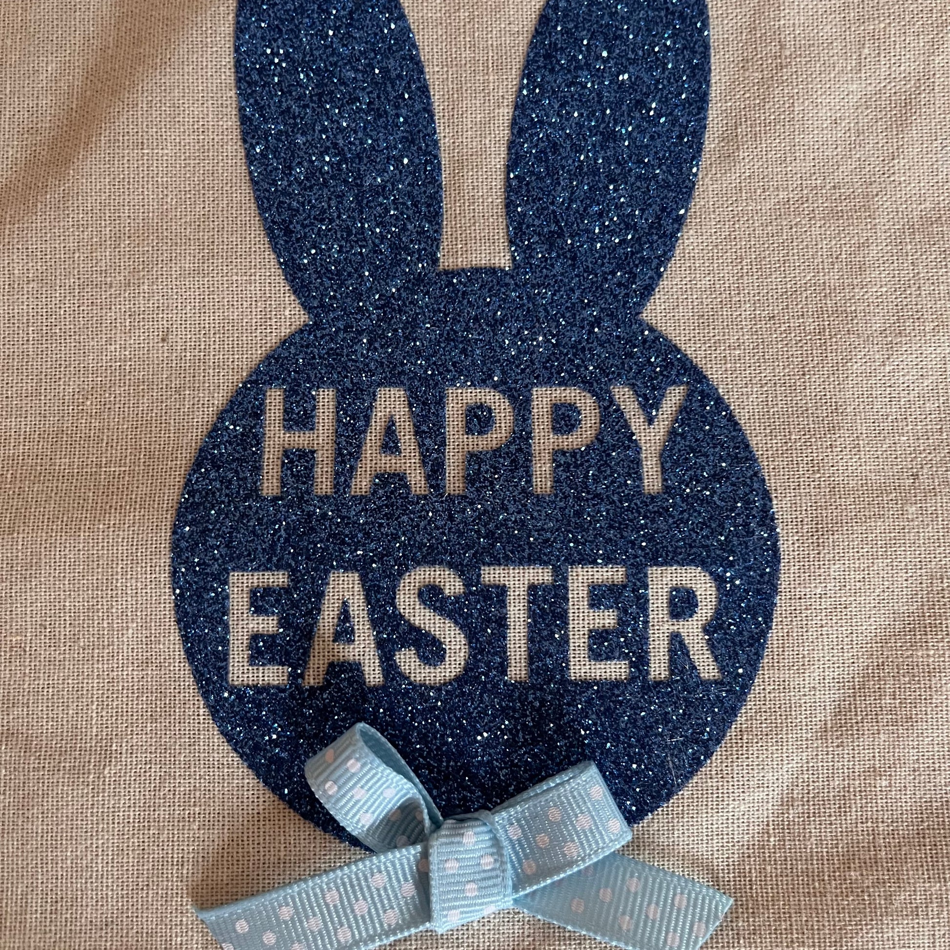 Happy Easter bunny design on burlap with a blue polka dot bow.