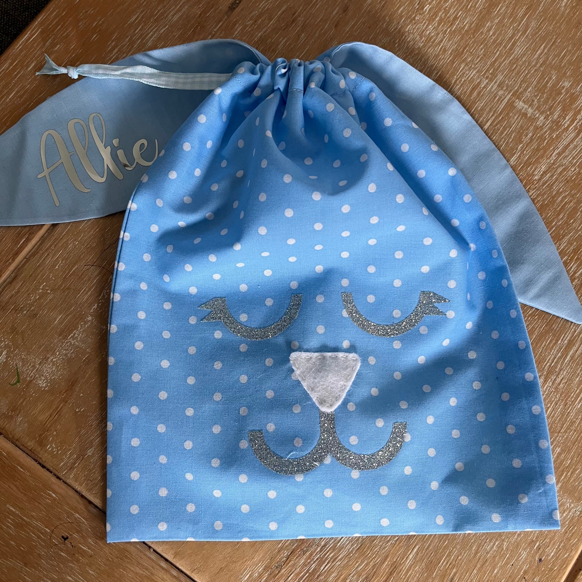 Blue polka dot drawstring bag with a bunny face design and the name Allie on one ear