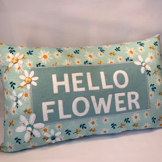 Hello Flower pillow with white felt letters and daisy print on a light blue background