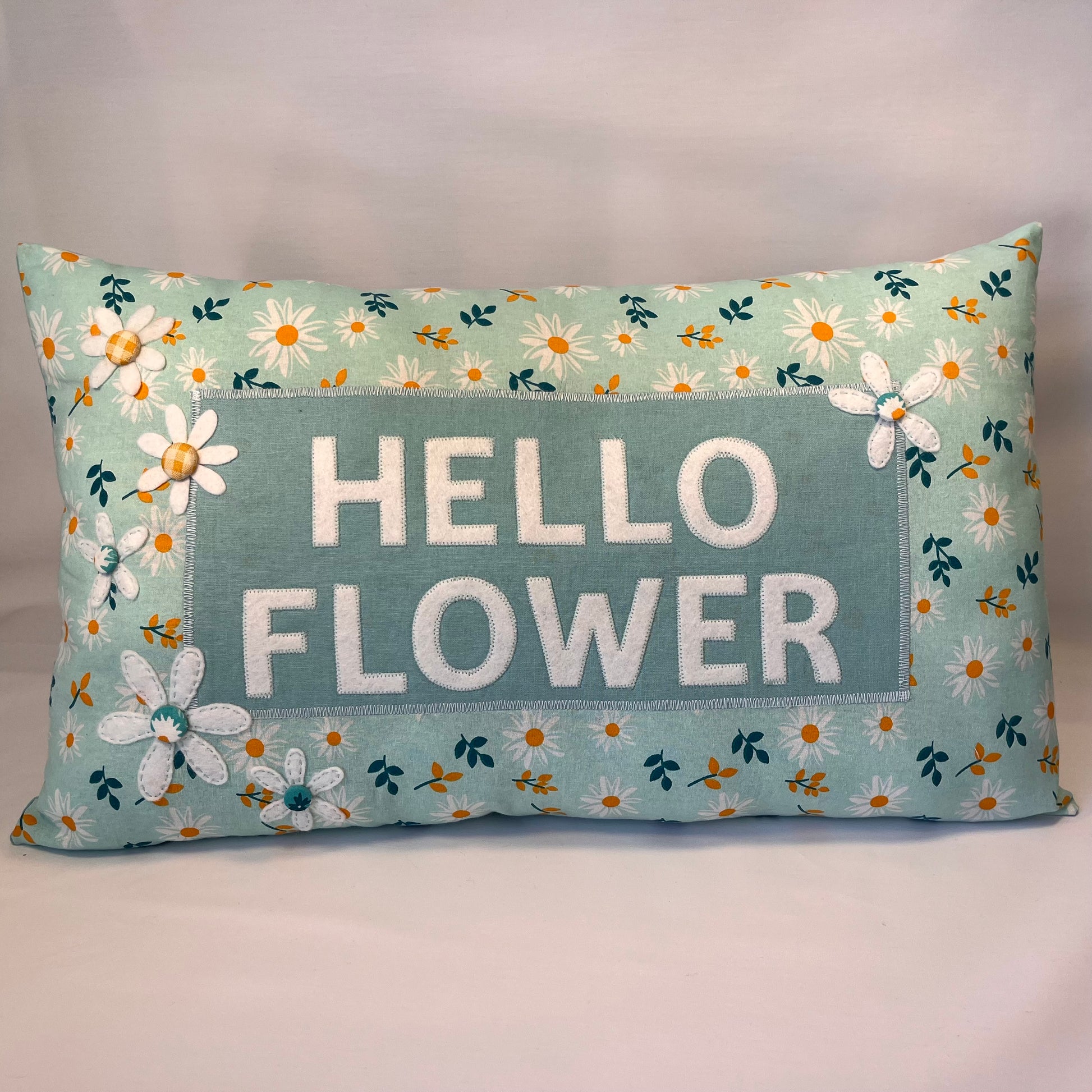 Hello Flower pillow with white daisy pattern and felt flowers