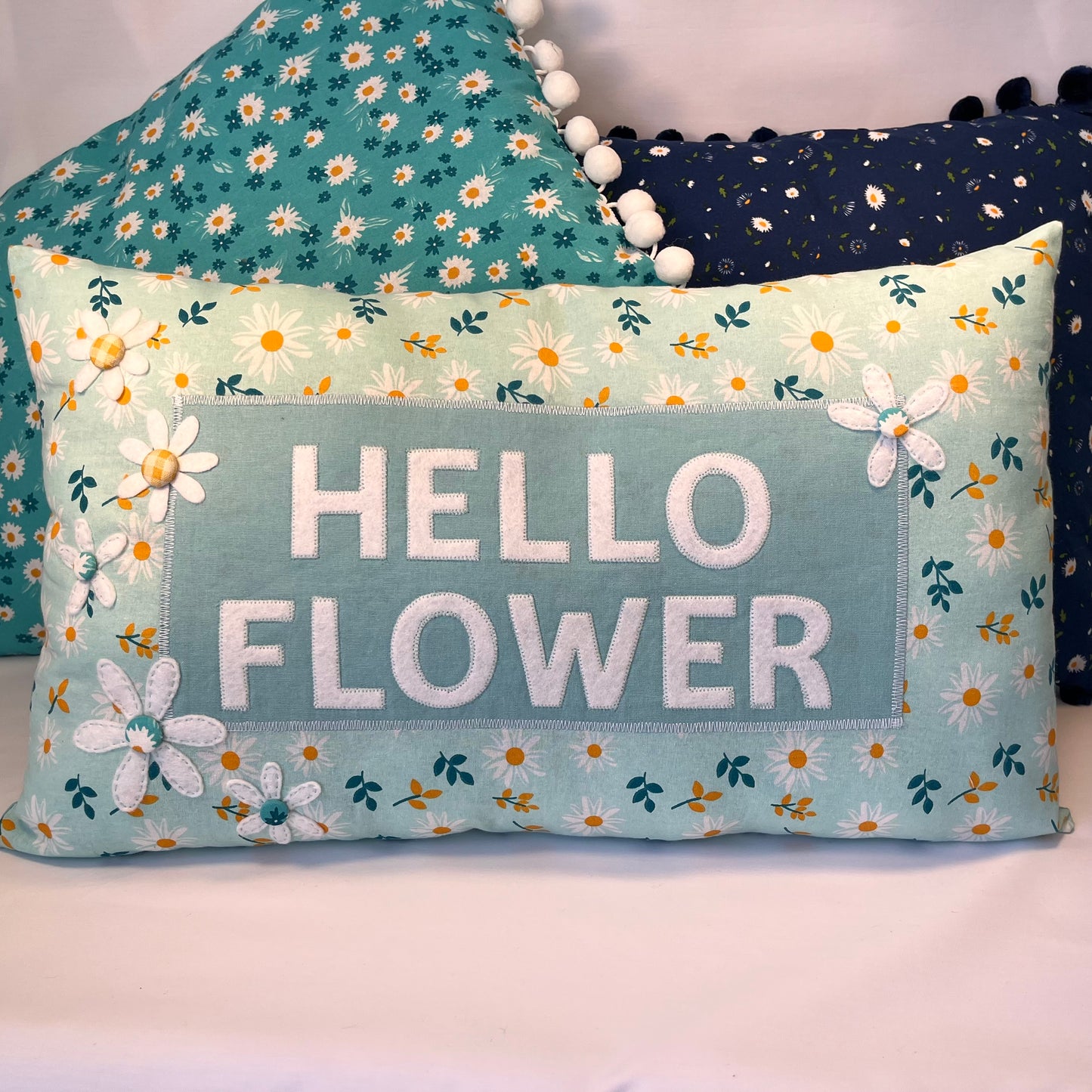 Hello Flower pillow with daisy pattern and pom-pom trim
