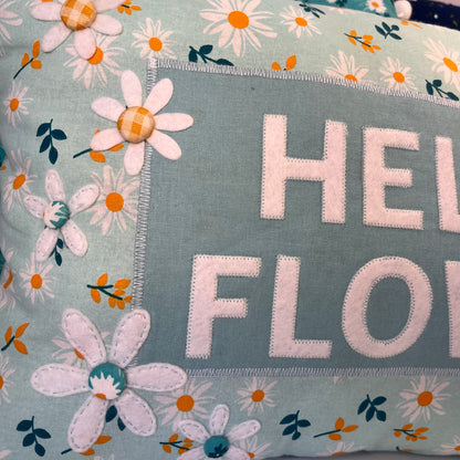Close up of a pillow with the words Hello Floral and daisy appliques