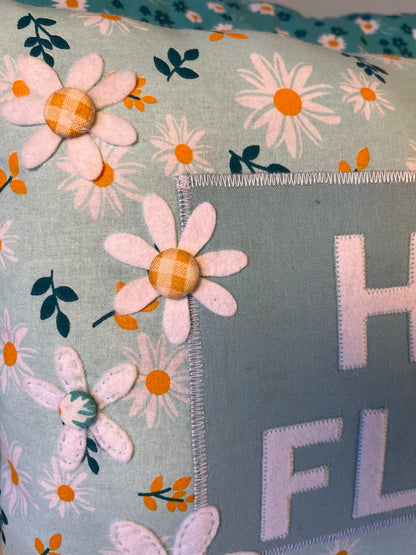 Close up of a pillow with a daisy pattern and felt daisies sewn on