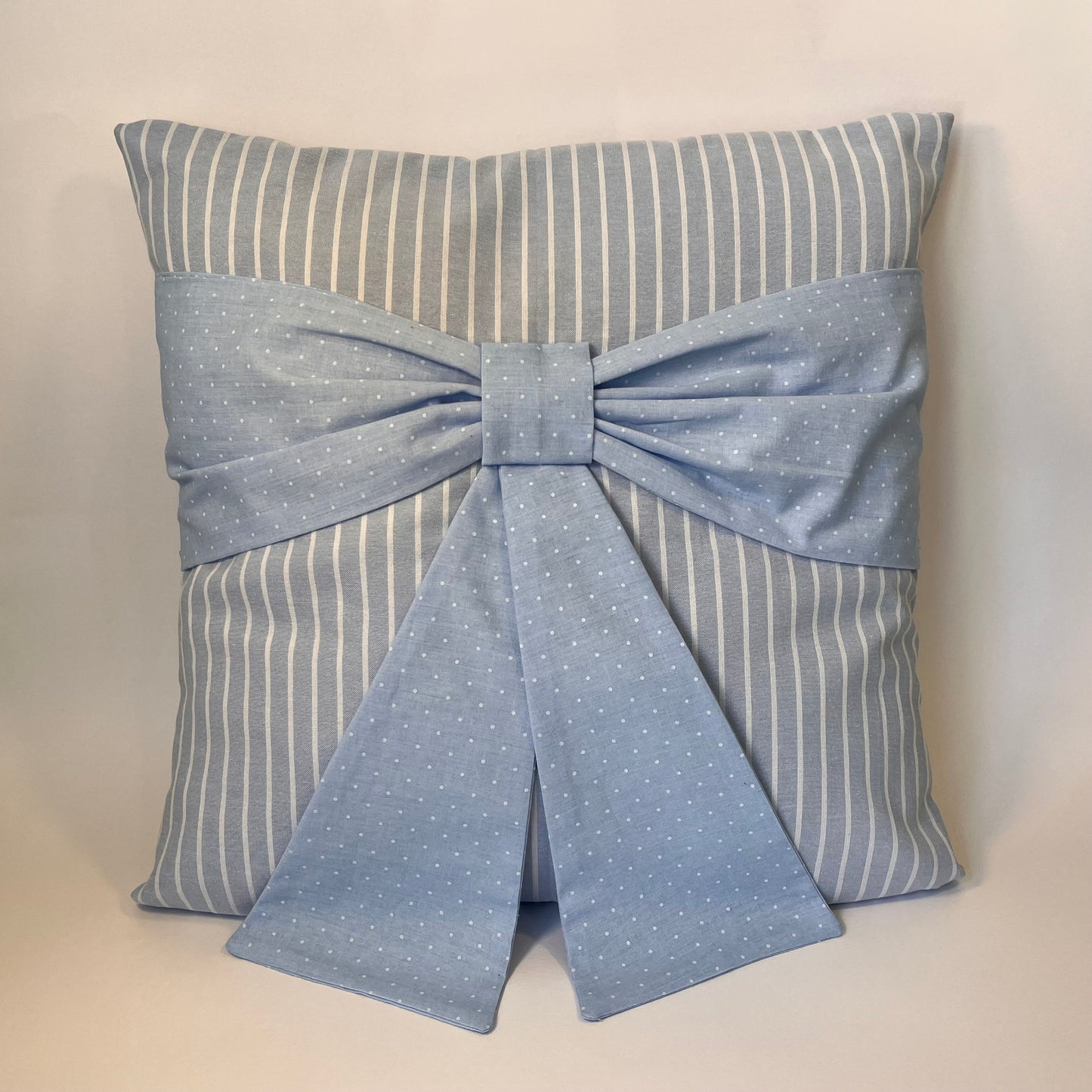 Blue and white striped pillow with a blue polka dot bow