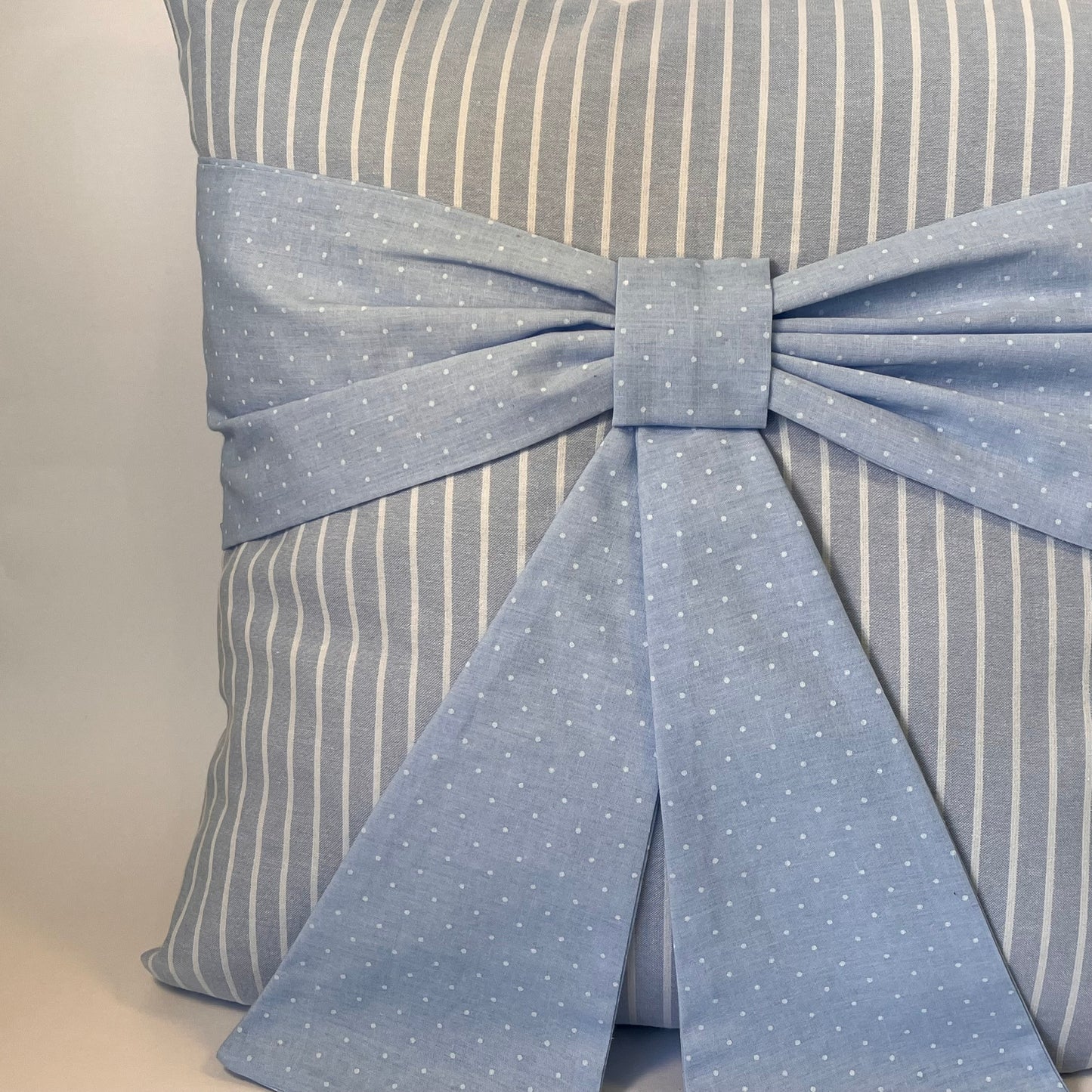 Blue and white striped cushion with a blue polka dot bow