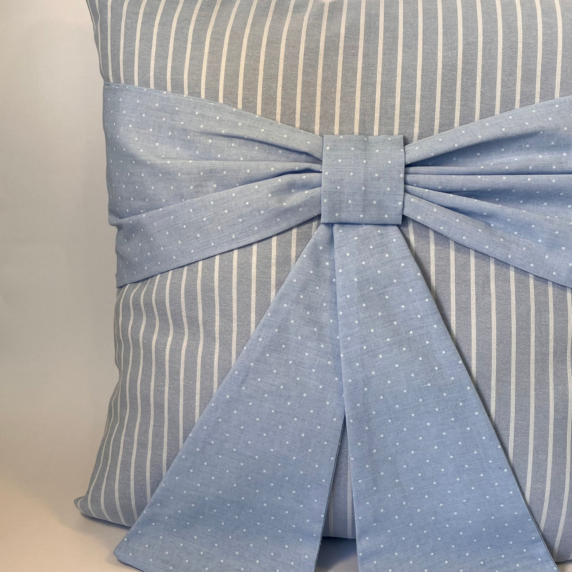 Blue and white striped cushion with a blue polka dot bow
