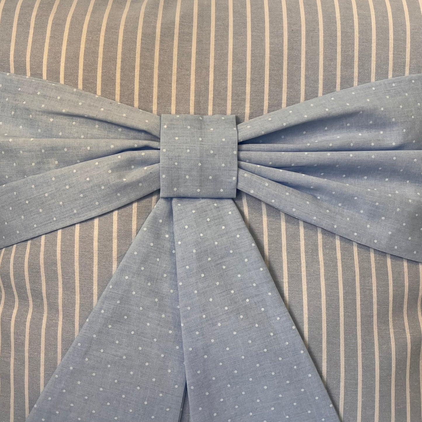 Blue polka dot bow on a grey and white striped fabric