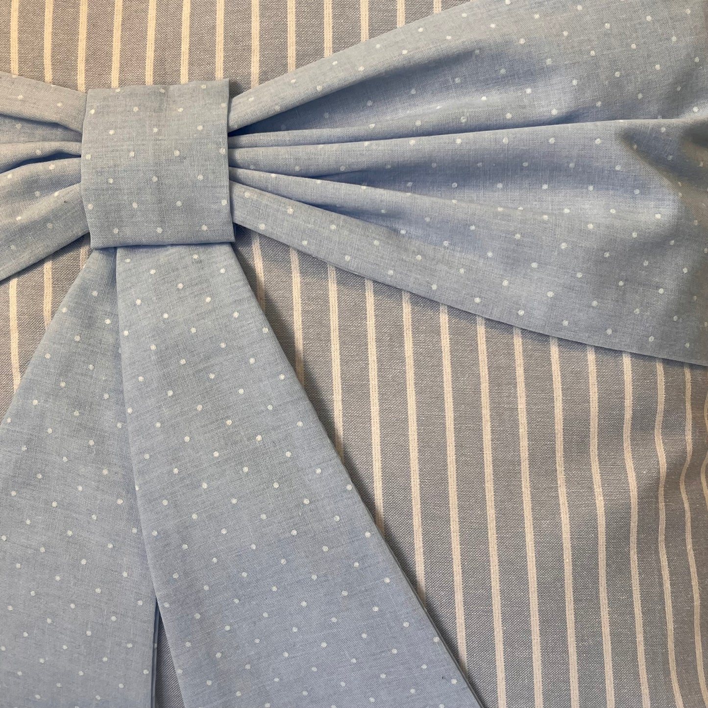 Blue polka dot bow on a grey and white striped fabric