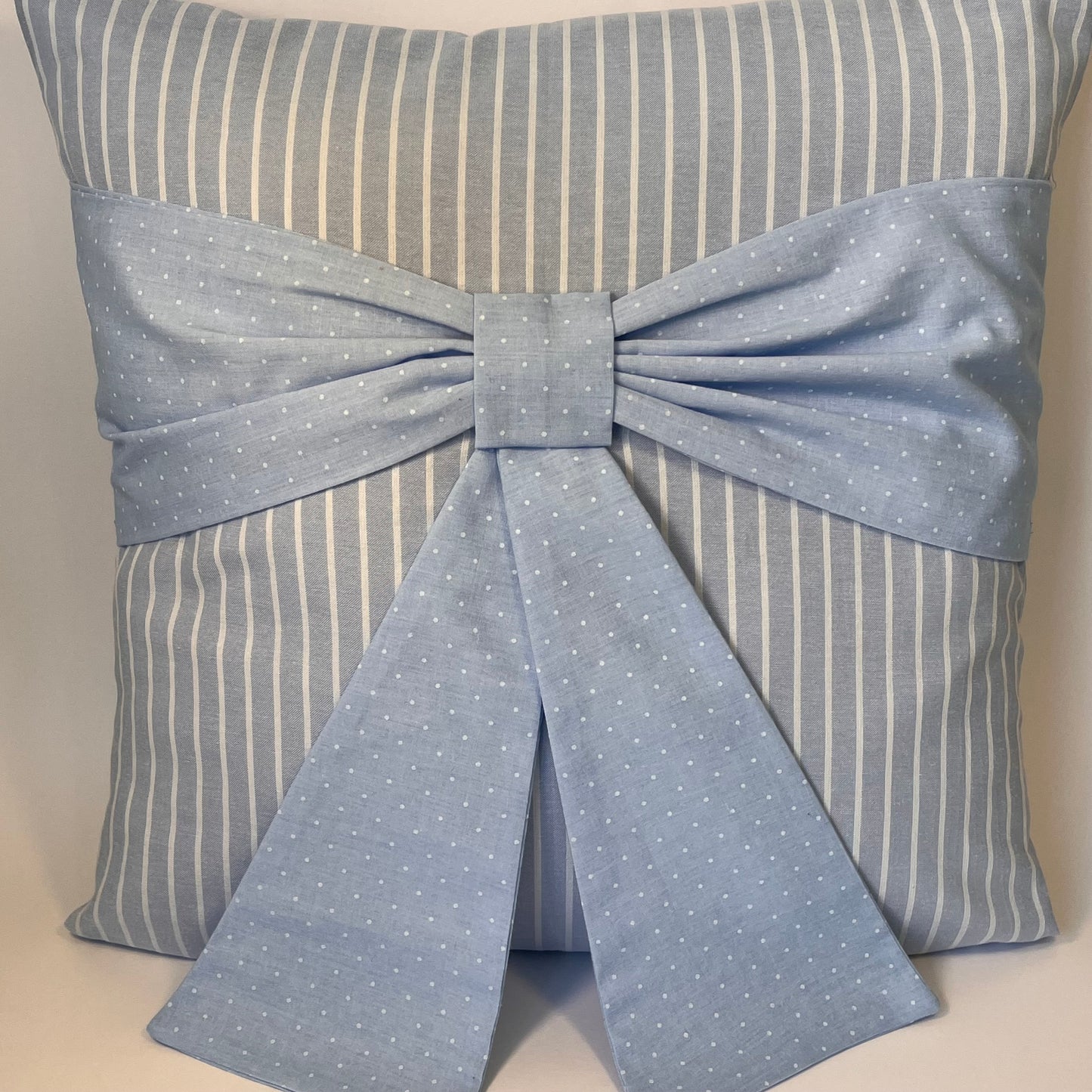 Blue and white striped pillow with a blue polka dot bow