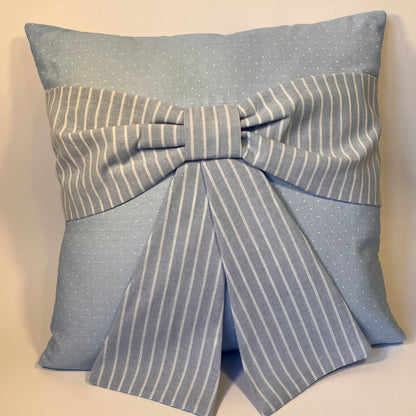 Light blue pillow with white polka dots and a large striped bow in the center