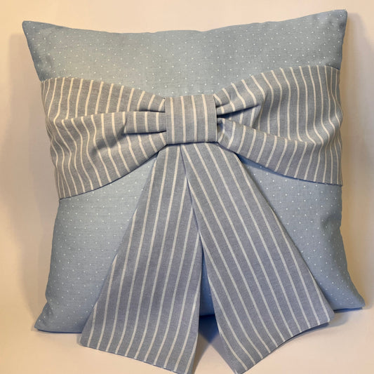 Light blue pillow with white polka dots and a large striped bow in the center