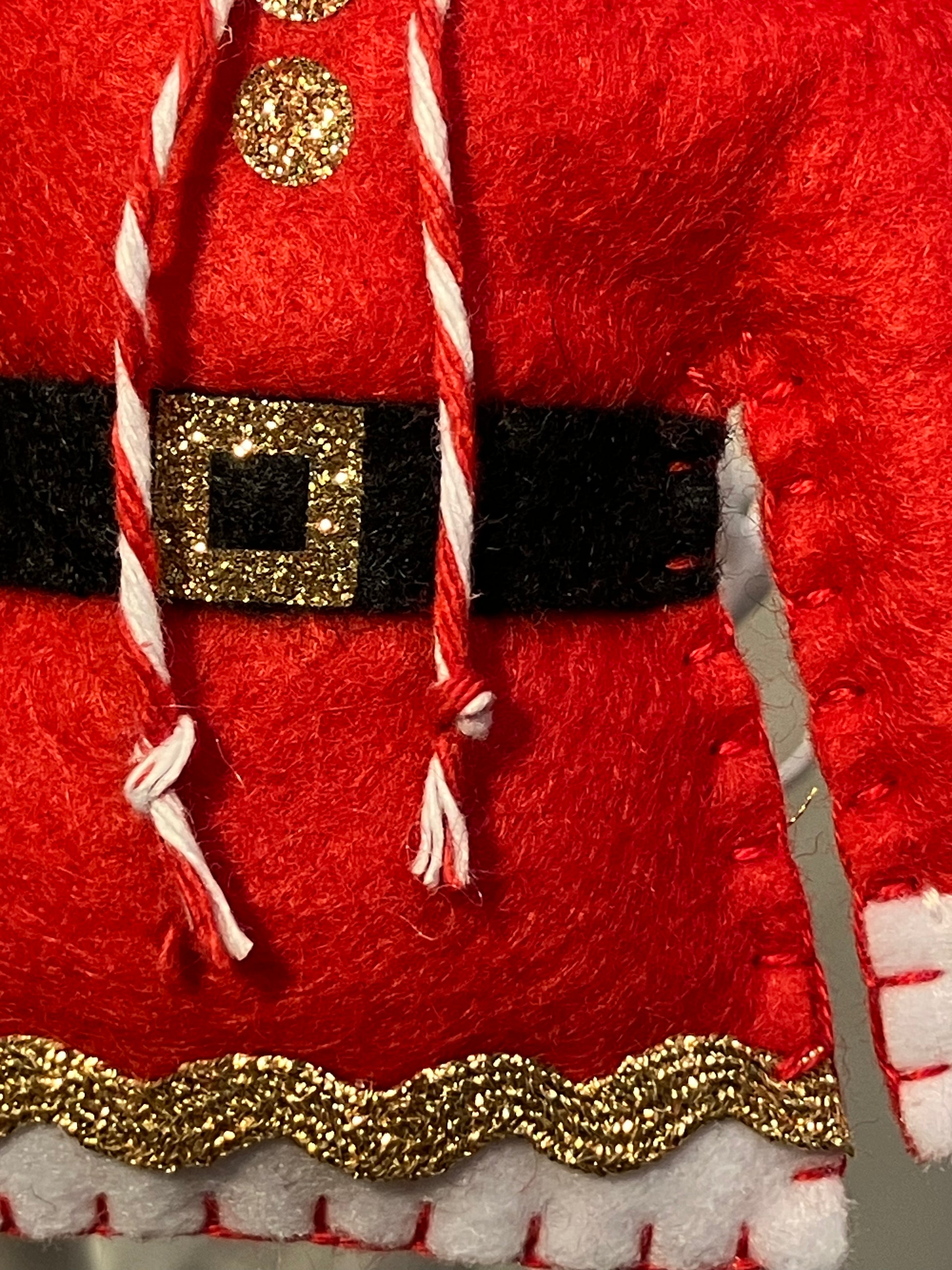 Close-up of the lower part of a red Santa jacket with a sparkly belt and trim.