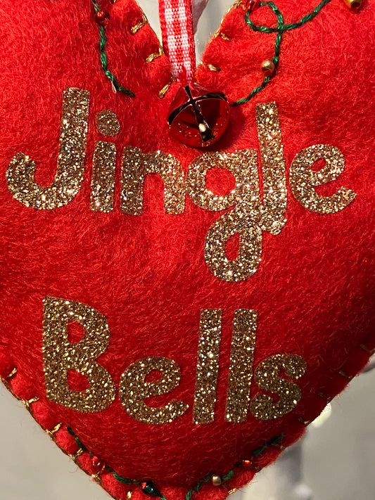 Close-up of the Jingle Bells text in gold glitter on a red felt heart ornament.