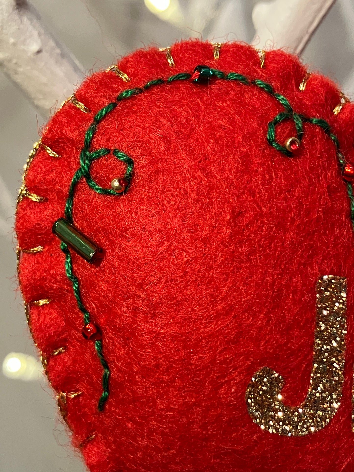 Close-up of the red felt heart ornament with green stitching detail.