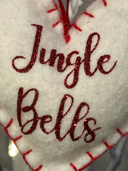 Close-up of the red glitter Jingle Bells text on a white felt heart ornament.