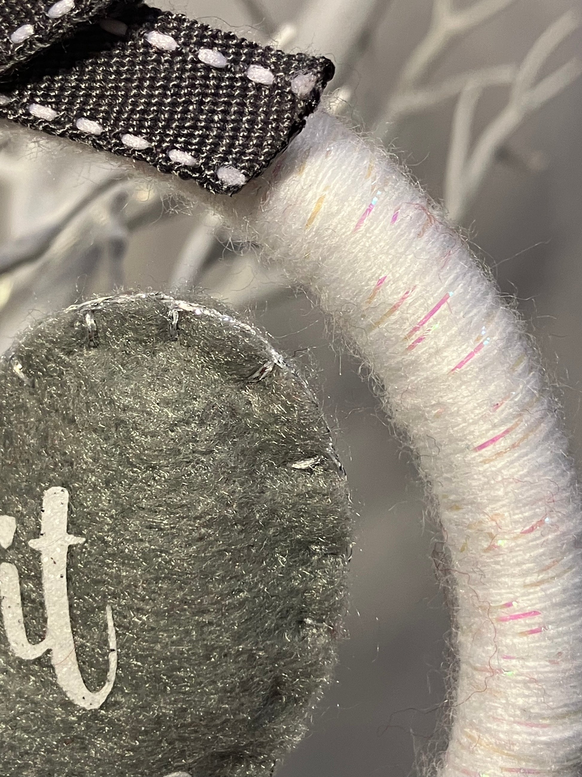 Close-up of the white yarn wreath and a corner of the gray felt heart.