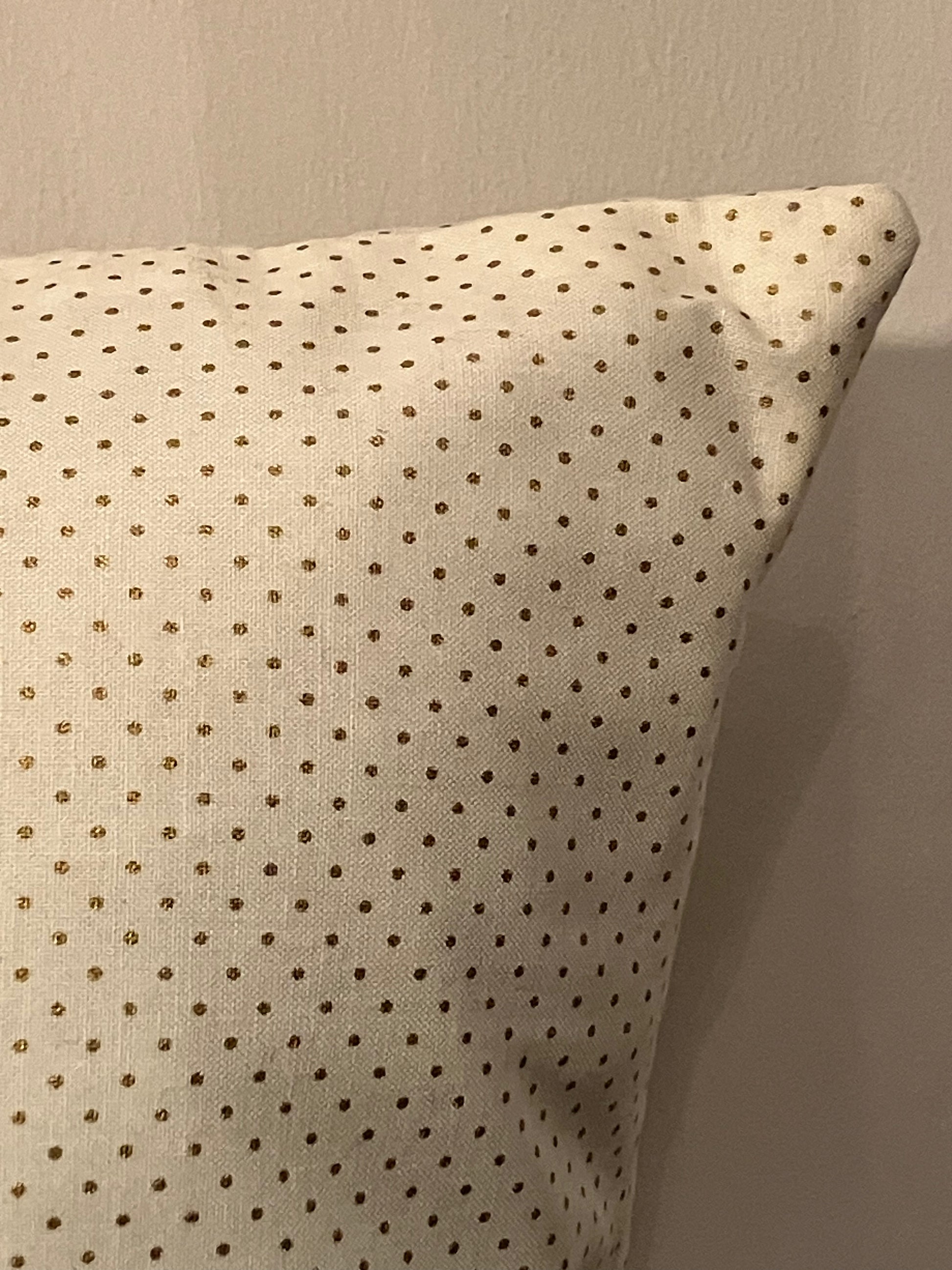 Close-up of the corner of the dotted white fabric pillow.