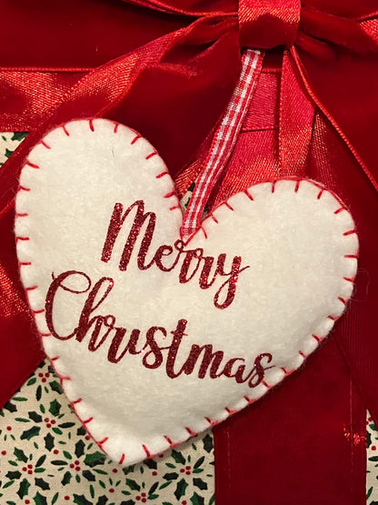 Detailed view of the 'Merry Christmas' heart-shaped tag on a festive cushion.