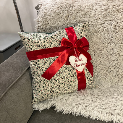 A festive cushion in a living room, decorated with a red ribbon and a 'Merry Christmas' tag.