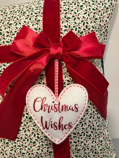 Close-up of a Christmas cushion featuring a red bow and a 'Christmas Wishes' heart.