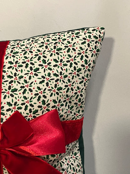 Corner of a festive Christmas cushion with a holly pattern and a red satin bow.
