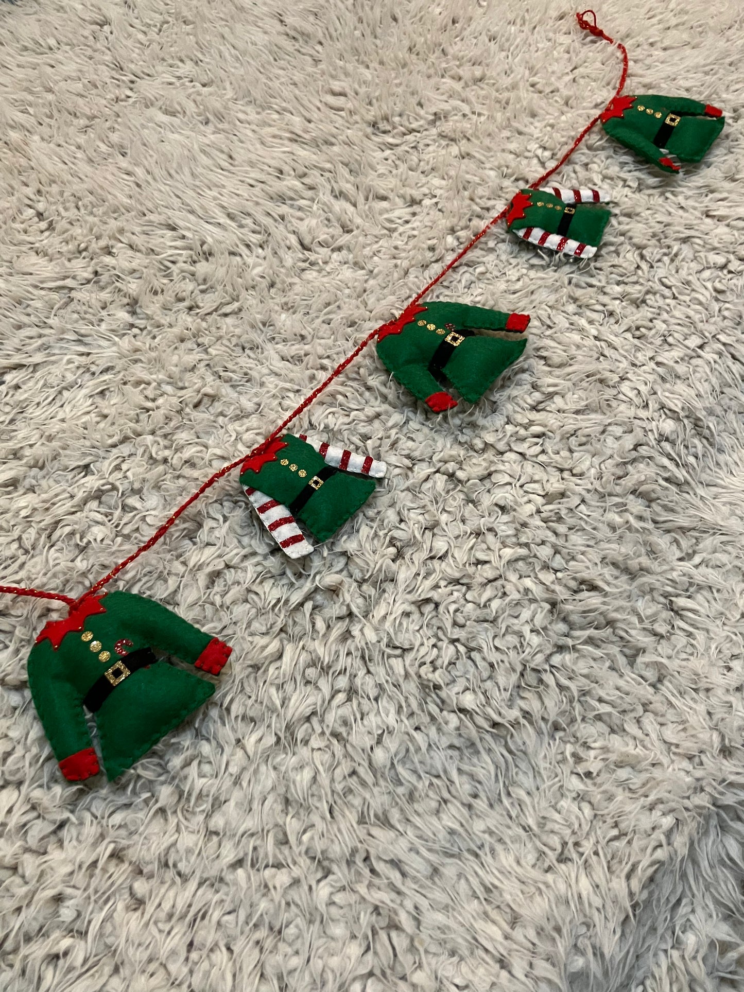 A horizontal Christmas elf outfit garland with varying elf outfits.
