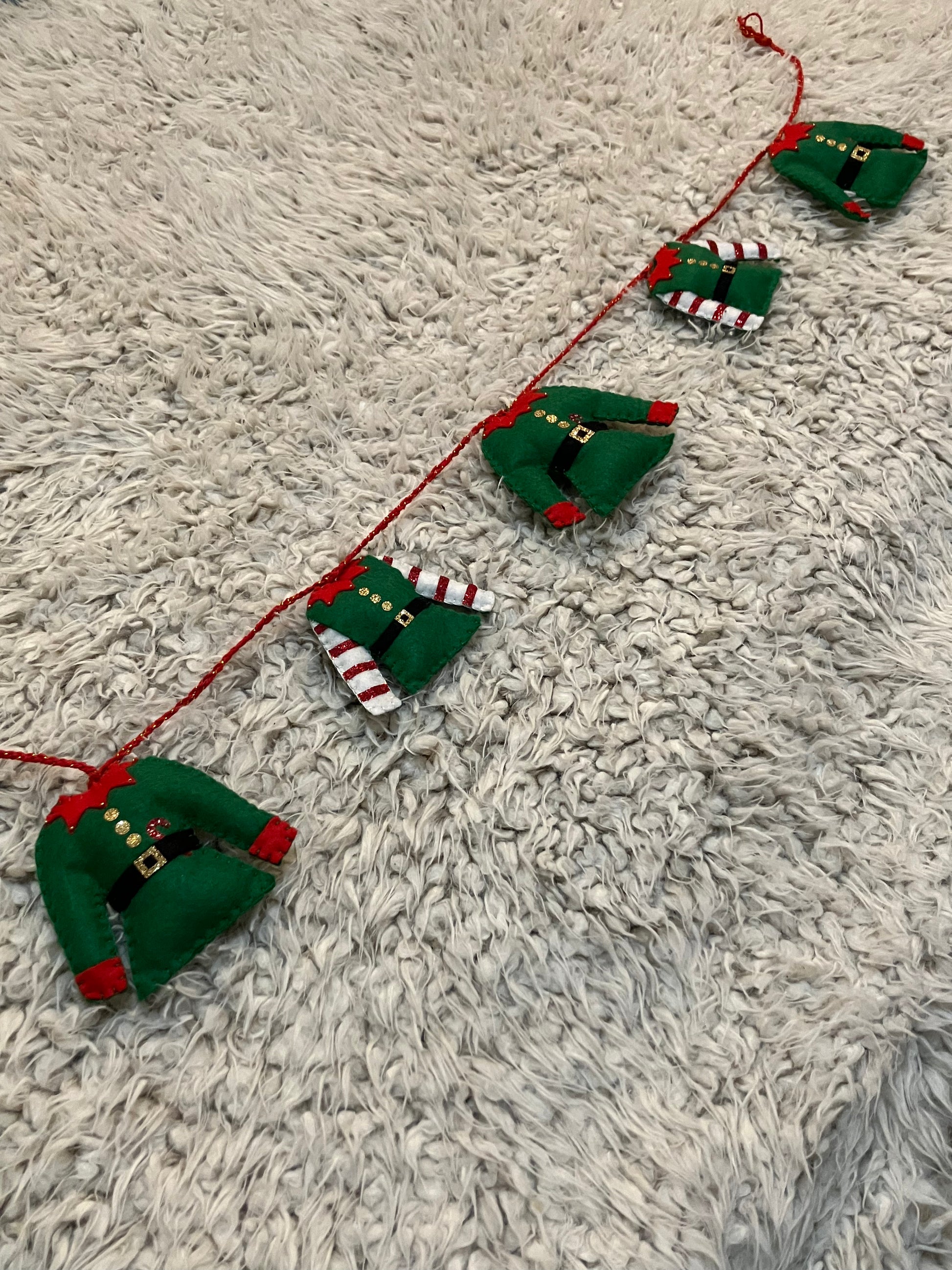 A horizontal Christmas elf outfit garland with varying elf outfits.