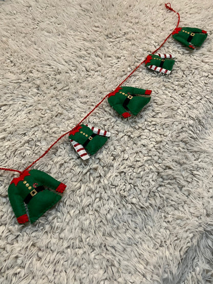 A horizontal Christmas elf outfit garland with varying elf outfits.