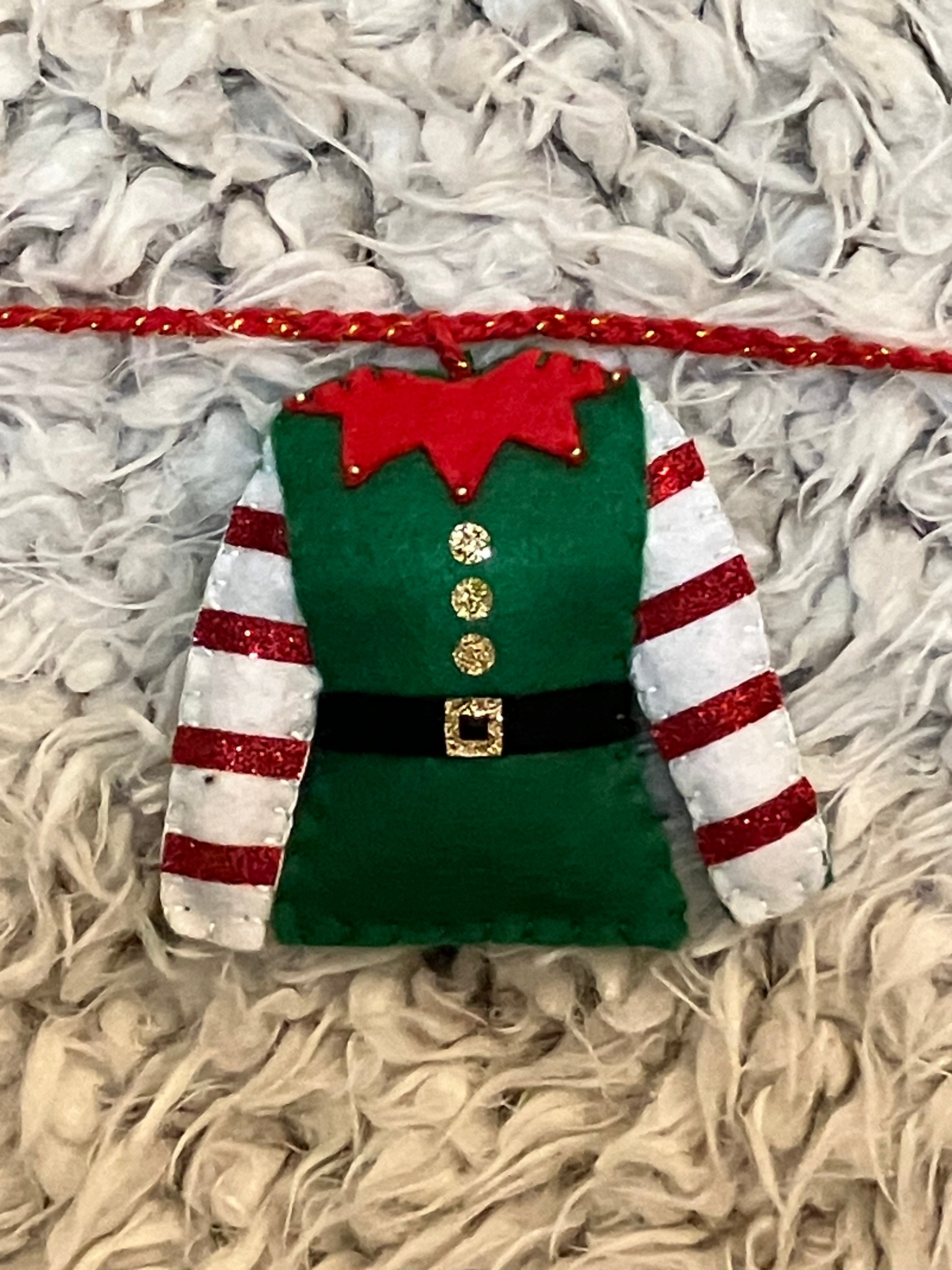 A closeup of a single green elf outfit with red and white striped sleeves.