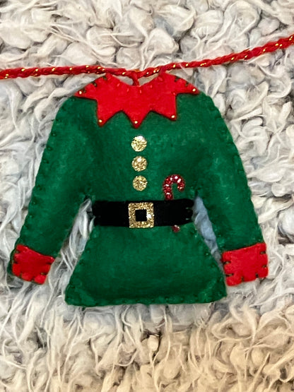 A closeup of a single green elf outfit with red trim, gold buttons, and a candy cane.