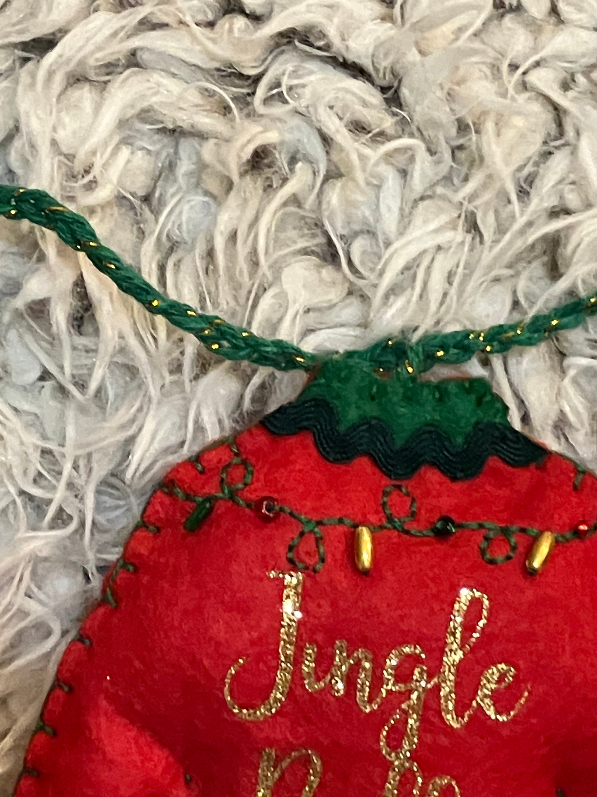Close-up of the green string and top of the red felt Jingle Bells Christmas sweater ornament.