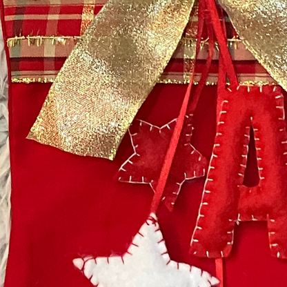 A red stocking with a gold bow, red felt letters, and white and red felt stars.