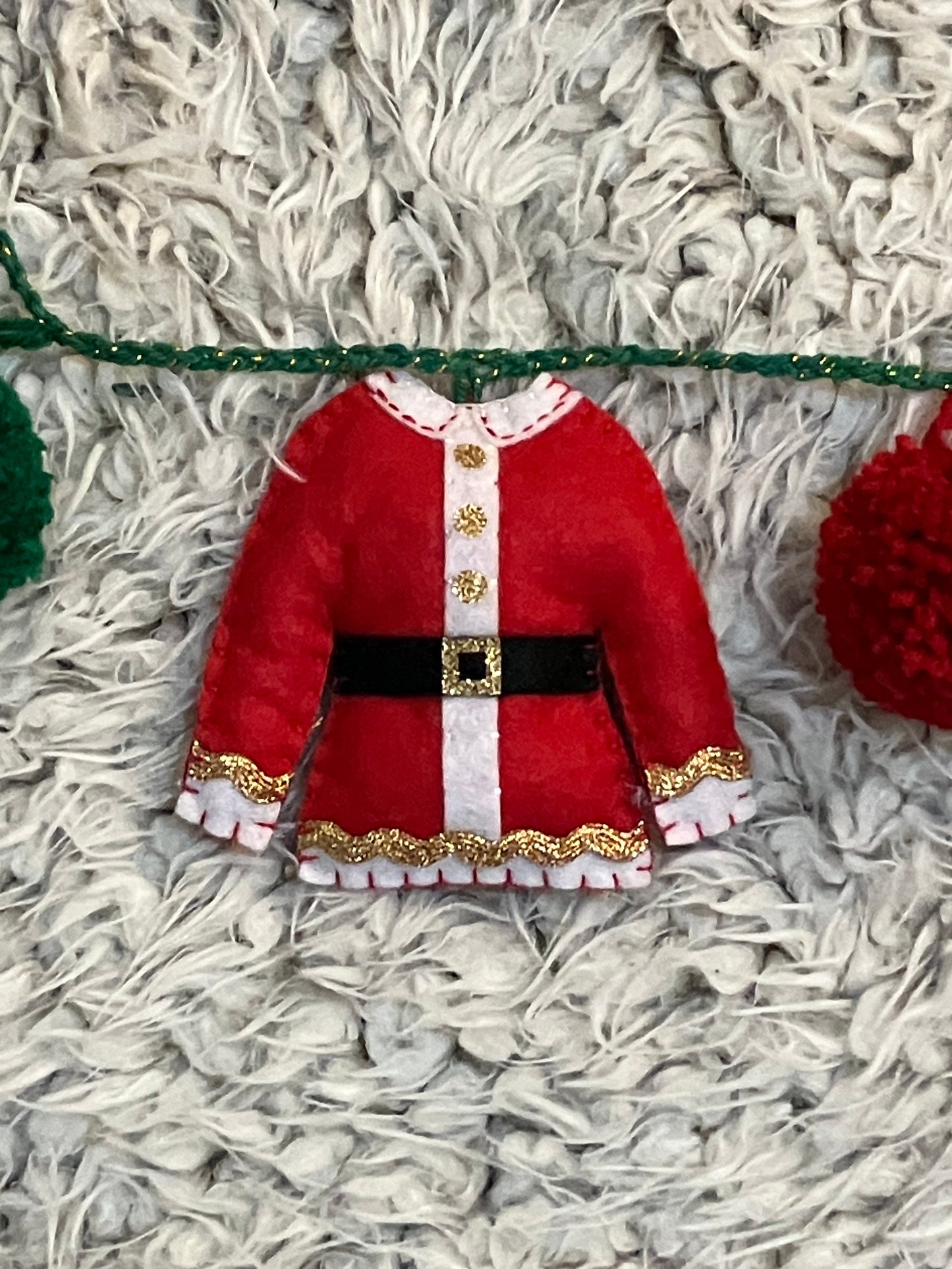 A miniature red Santa Claus jacket with gold trim and a black belt.