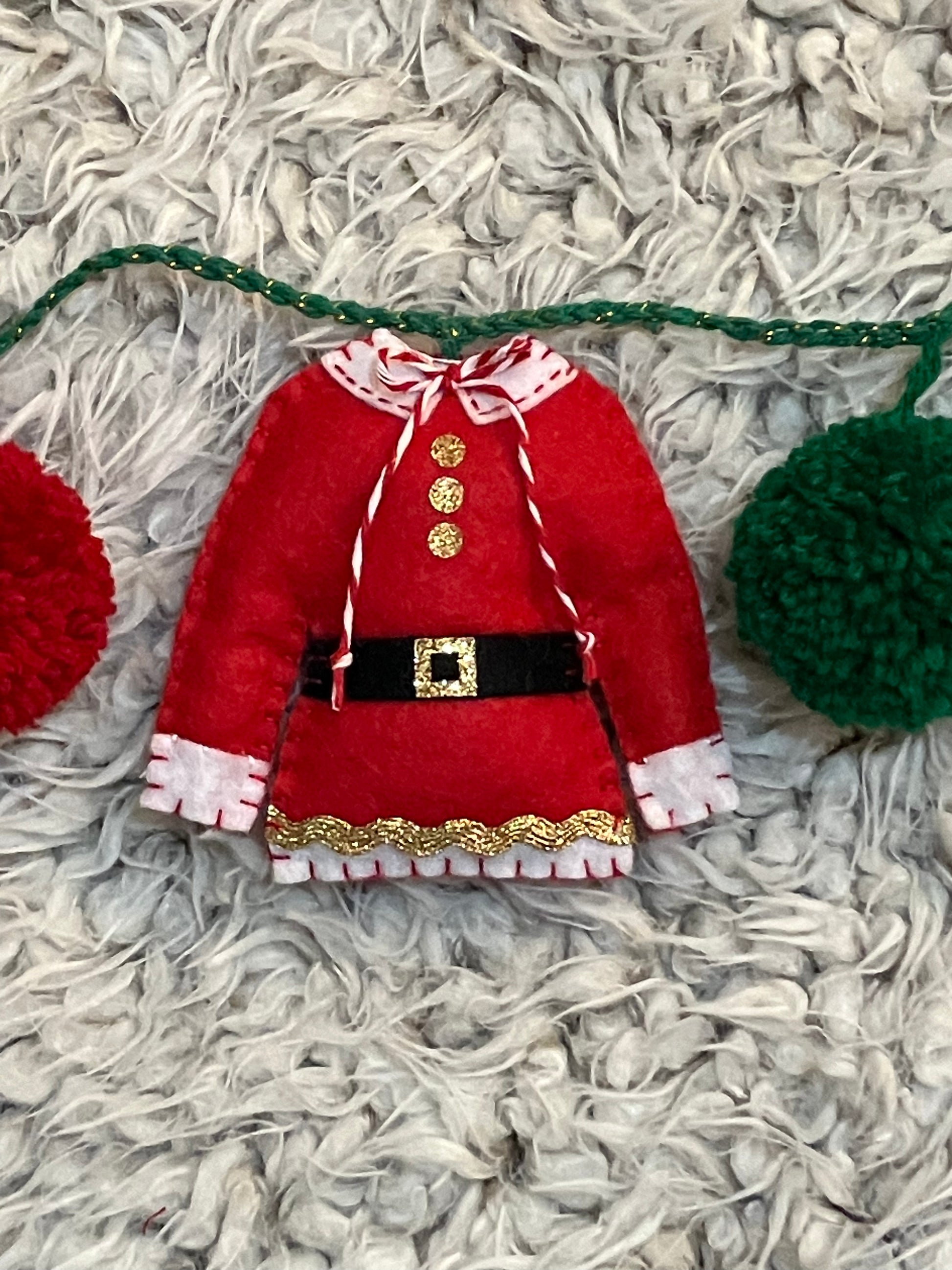 A miniature red Mrs. Claus jacket with a white collar and gold trim.