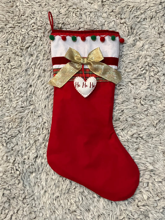 Full view of a red and white Christmas stocking with a gold bow and "Ho Ho Ho" heart.