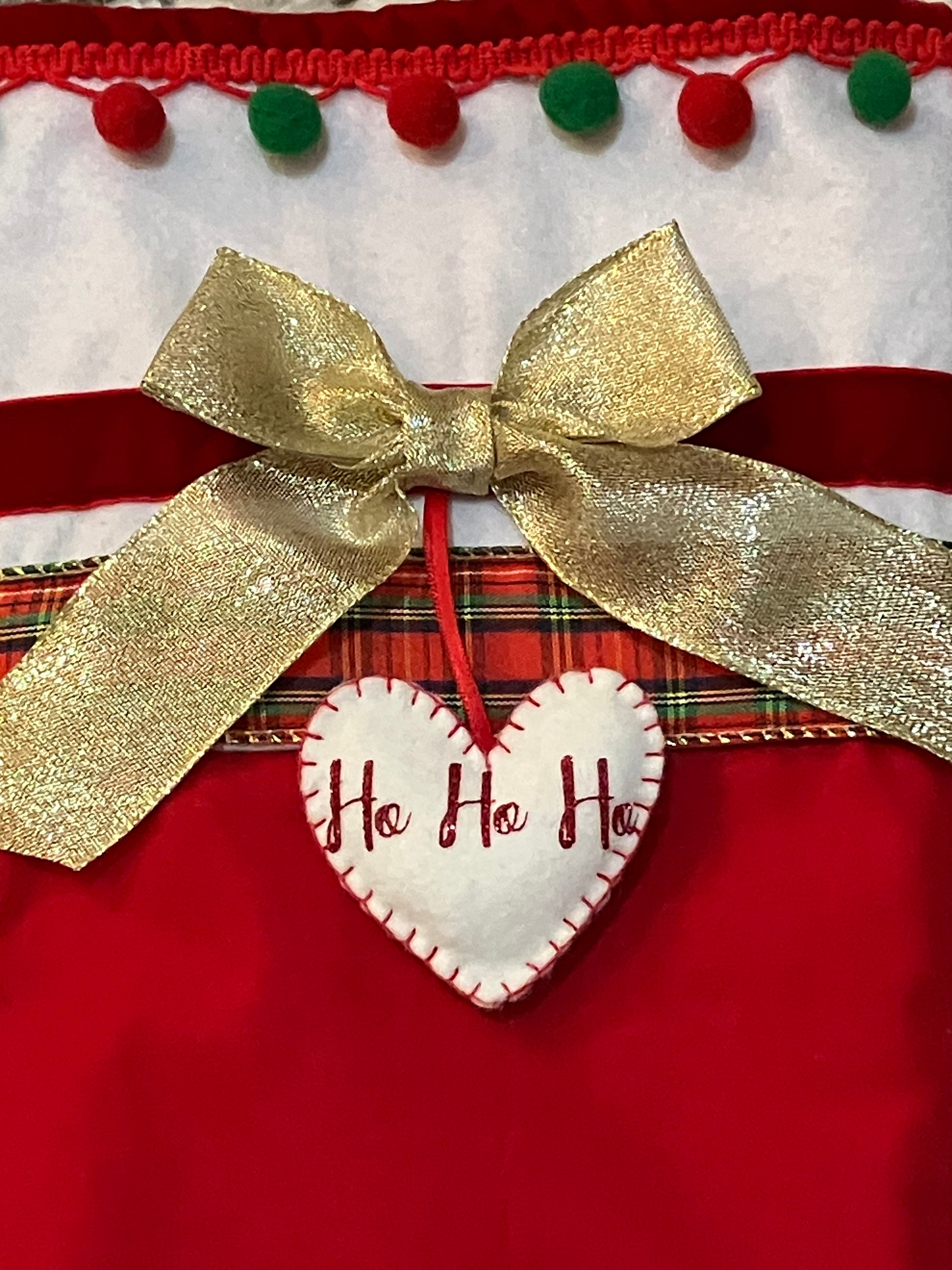Close-up of the gold bow and "Ho Ho Ho" heart on the Christmas stocking.